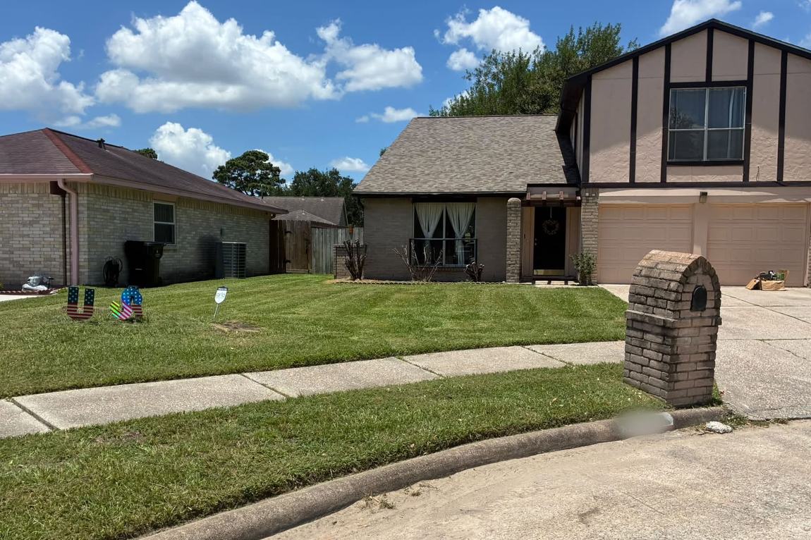 Freshly mowed and edged front lawn of a two-story brick home